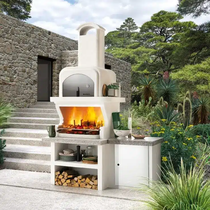 Barbecue in muratura con forno e fuoco acceso in giardino